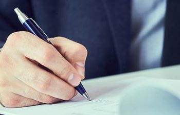 Hand of businessman in suit filling and signing with blue pen