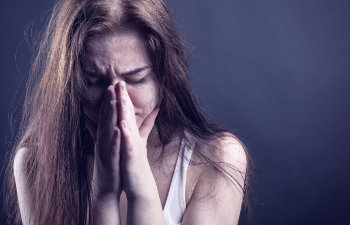 long haired brunette cries hiding face in hands