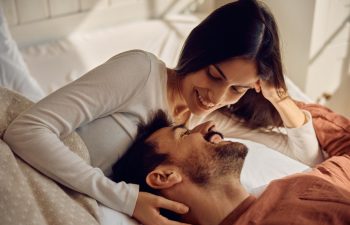 Happy couple in love communicating face to face while relaxing on a bed.